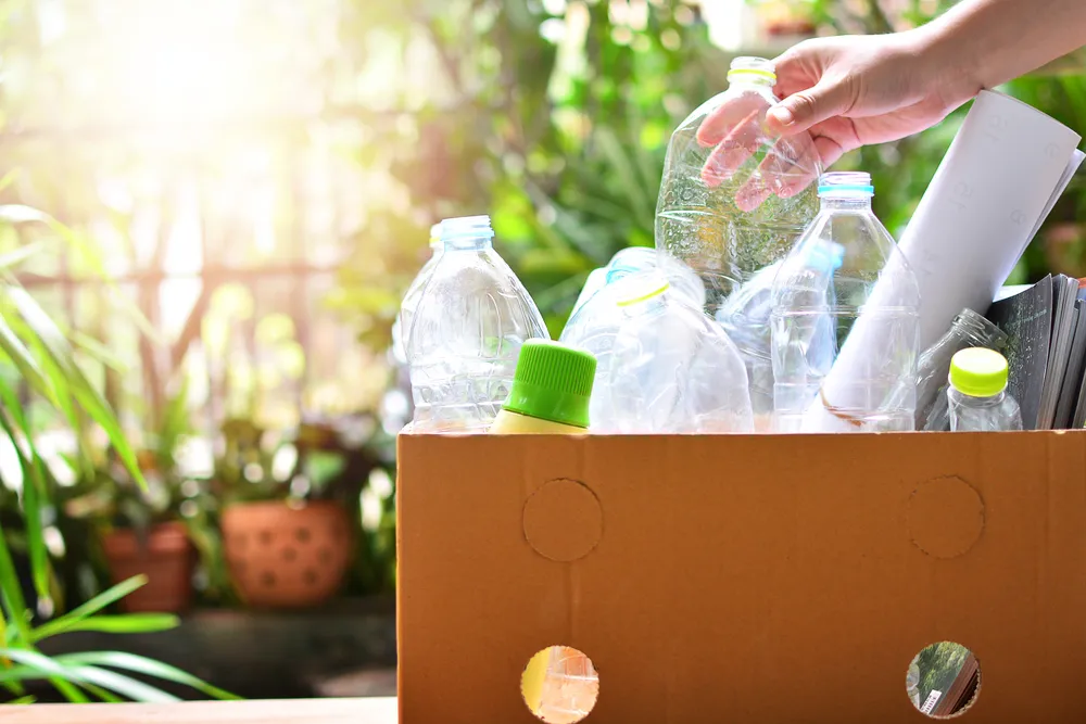 Hands sorting recyclable bottles into bins