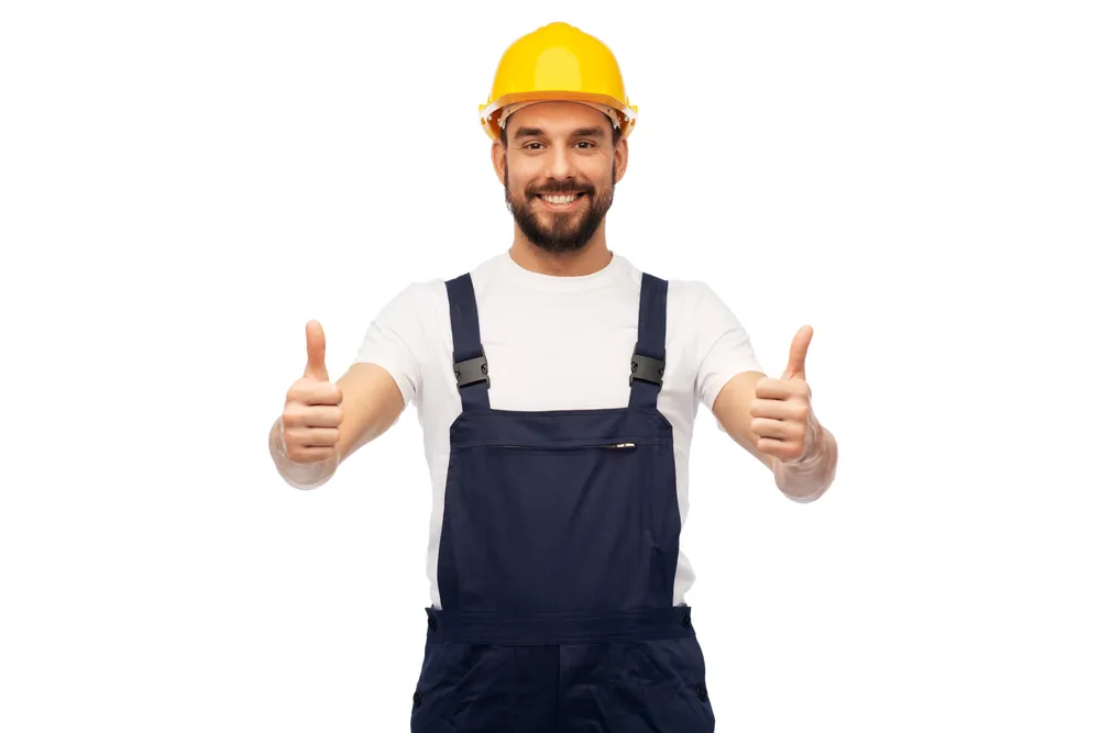Smiling worker in a hard hat giving two thumbs up